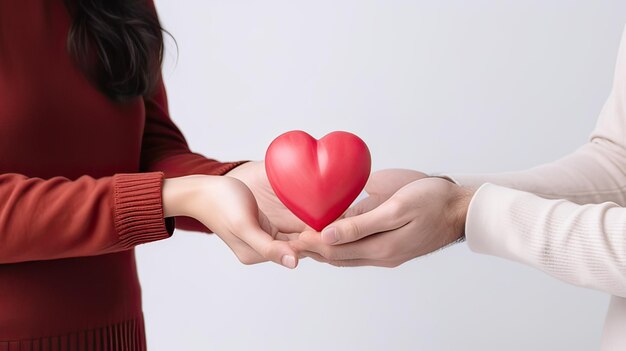 um homem segura em suas mãos um modelo de um coração vermelho em um fundo rosa o conceito de amor