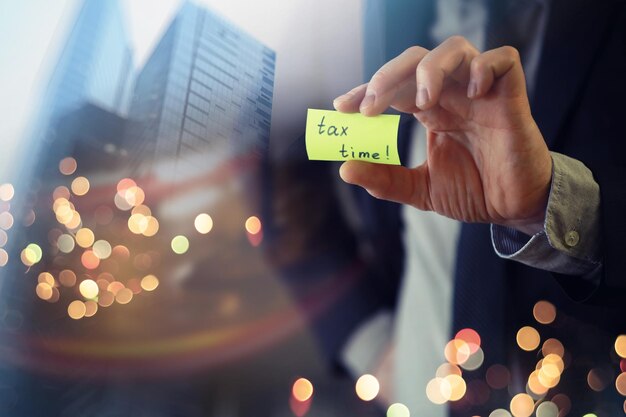 Um homem segura um post-it amarelo que diz hora do imposto.