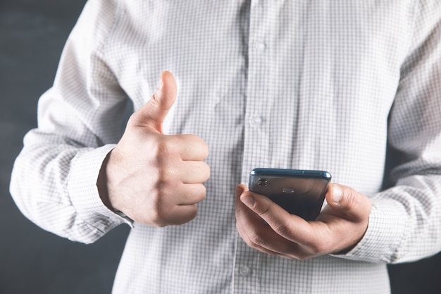 Um homem segura um telefone e mostra um bom sinal