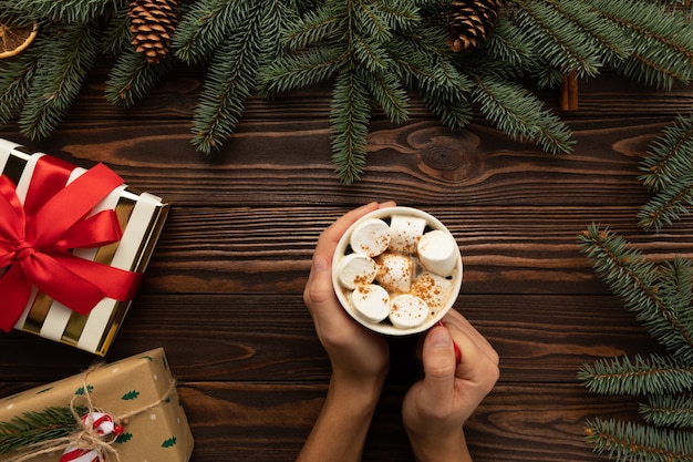 Um homem segura uma bebida quente de Natal com marshmallows e canela nas mãos