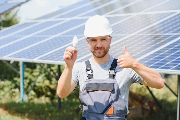 Um homem segura uma lâmpada incandescente em seu conceito de energia o sol está limpo após o trabalho e substitui a energia que produz dióxido de carbono