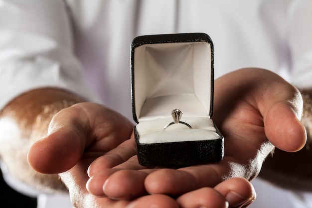 Um homem segurando um anel de diamante em um gesto de doação.