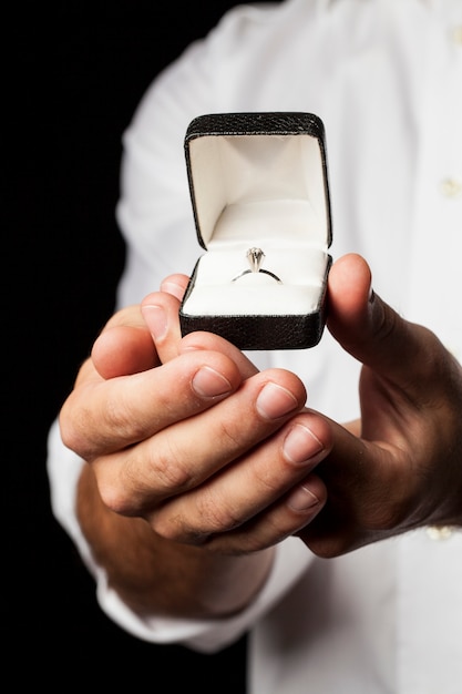 Um homem segurando um anel de diamante em um gesto de doação.