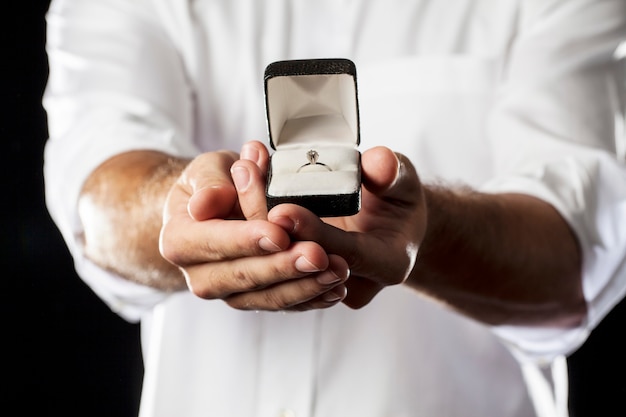 Um homem segurando um anel de diamante em um gesto de doação.