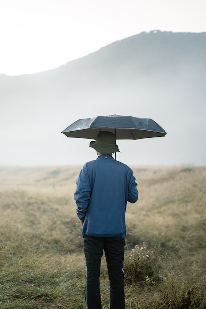 Um homem segurando um guarda-chuva em uma montanha com névoa