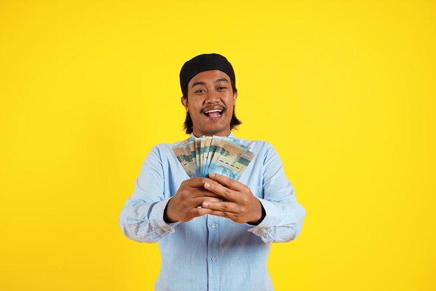 Um homem segurando um monte de moeda indonésia com um grande sorriso após o dia de pagamento e férias