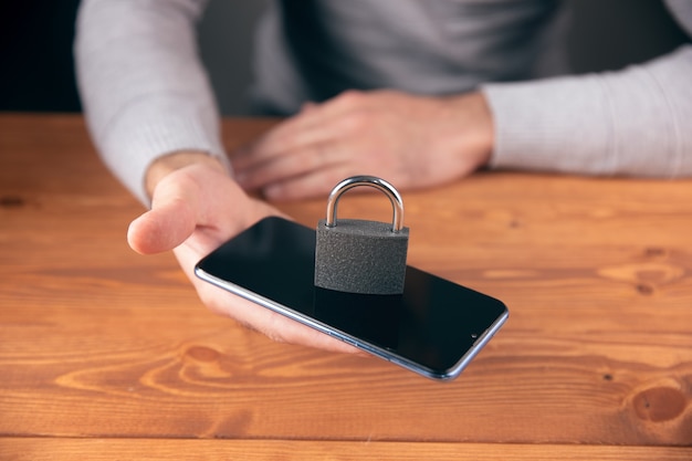 Um homem segurando um telefone e uma fechadura