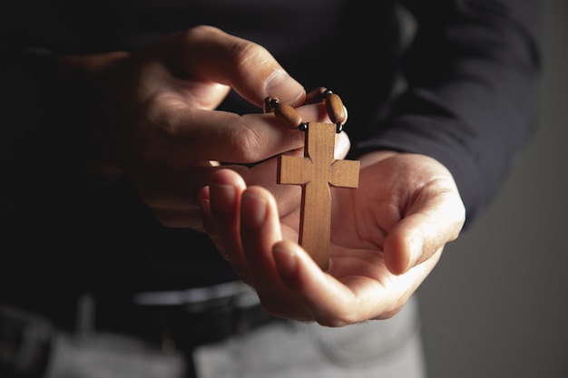 Um homem segurando uma cruz de madeira na mão