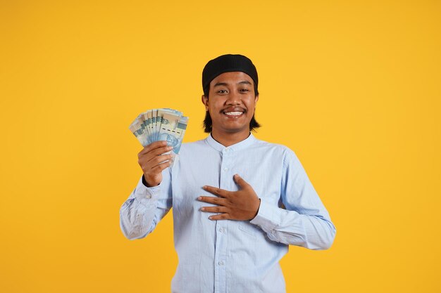 Um homem segurando uma pilha de dinheiro na frente de um fundo amarelo