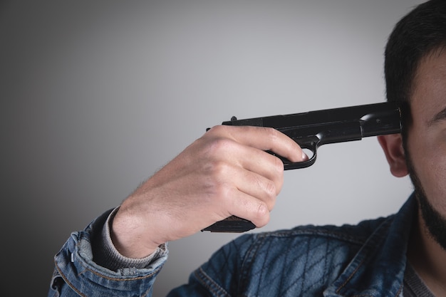 Um homem segurando uma pistola preta na mão ameaçando