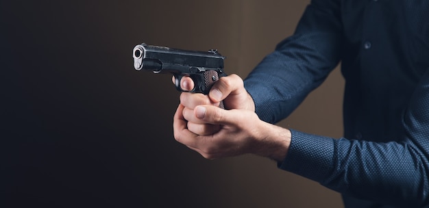 Um homem segurando uma pistola preta na mão ameaçando