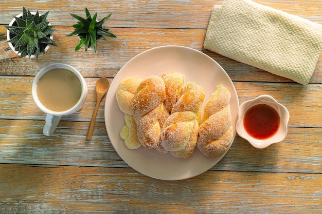 Um homem segurando uma xícara de café preto e um copo de suco de laranja e pão de croissants