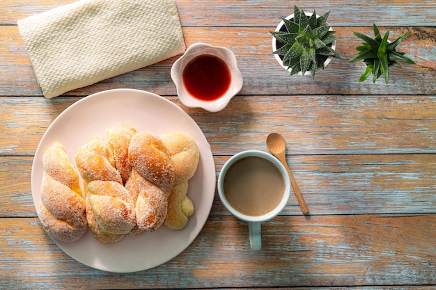 Um homem segurando uma xícara de café preto e um copo de suco de laranja e pão de croissants