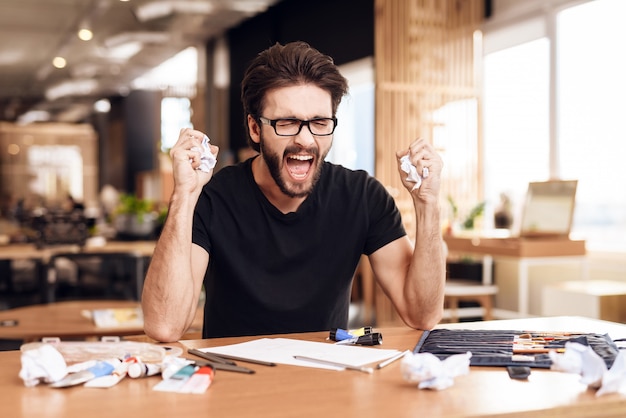 Um homem senta no escritório e grita do trabalho.