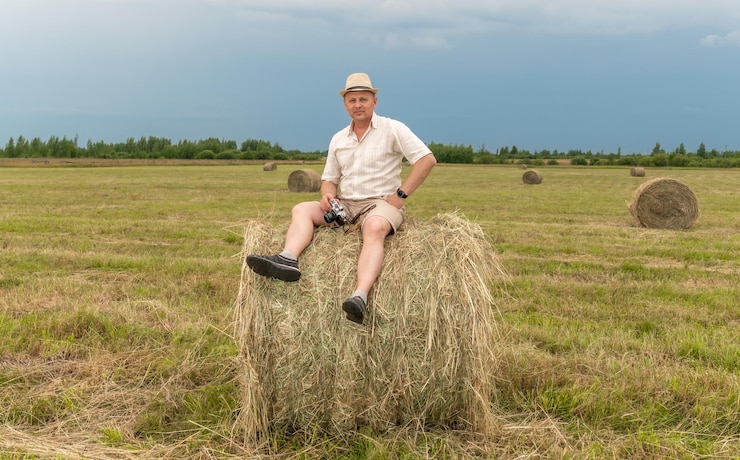 Foto um homem senta-se em um fardo de feno em um campo
