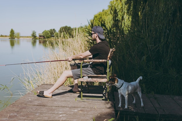 Um homem senta-se pescando perto de um lago