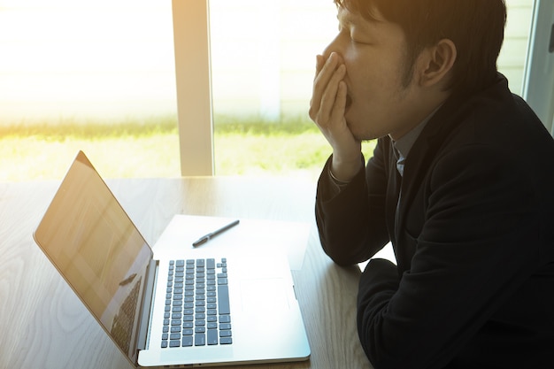 um homem sentindo sono e bocejando de cansaço e trabalho árduo