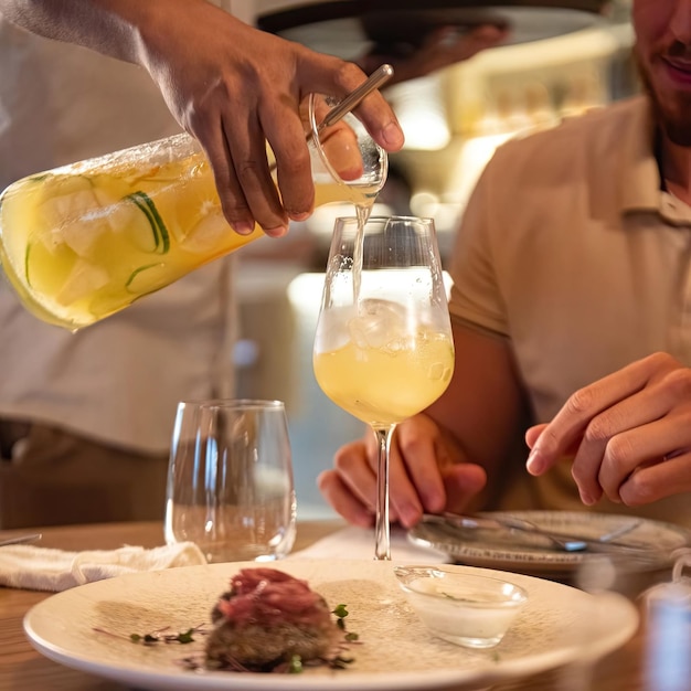 Um homem servindo uma bebida em um copo com uma garrafa de suco de laranja.