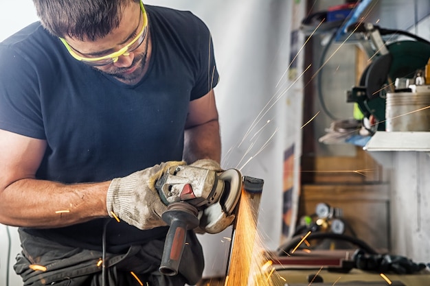 Um homem soldador trabalha duro e fabrica moedor de metal e esmerilhadeira