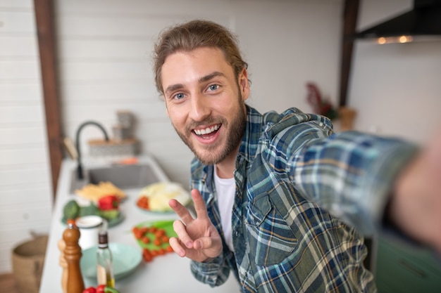 Um homem sorridente fazendo selfie na cozinha