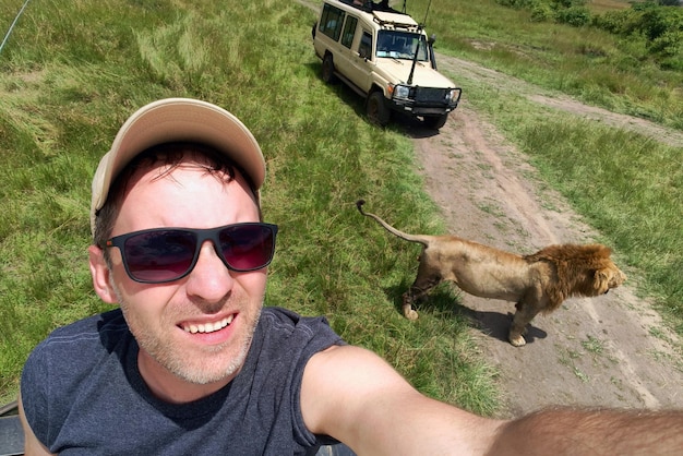 Um homem tira uma selfie com um leão selvagem durante um safári africano na natureza Um homem é fotografado com animais selvagens no Quênia