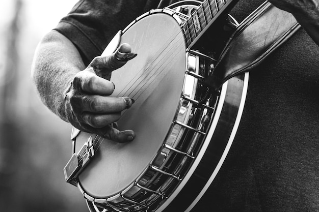 Foto um homem toca banjo com a mão enluvada.