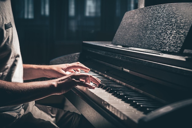 Um homem toca um piano eletrônico em um quarto escuro