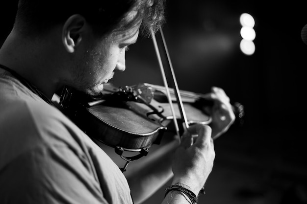 Um homem toca violino no palco do close