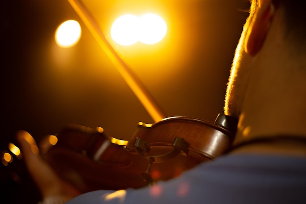 Um homem toca violino no palco do close