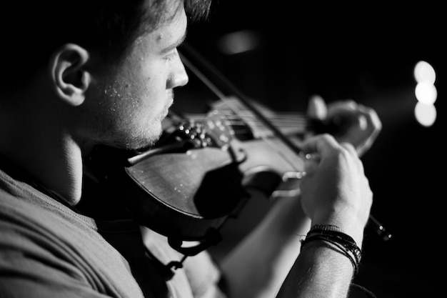 Um homem toca violino no palco do close