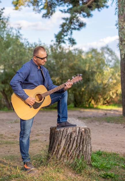 Foto um homem tocando violão na floresta