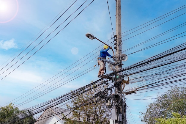 Um homem trabalhando em uma linha de energia com um poste de luz.