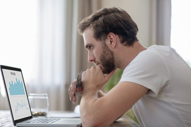 Um homem trabalhando sentado em frente ao laptop e parecendo frustrado