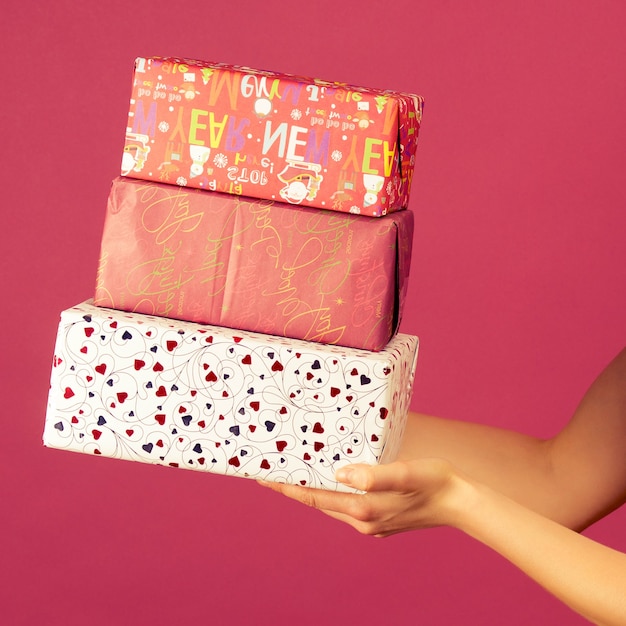 Um homem transgênero atlético bonito em um chapéu de ano novo e vestido branco, segurar em presentes de mãos. celebração do natal ou ano novo com fundo rubi