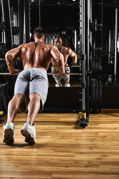 Um homem treina os braços e o peito no ginásio no simulador, faz exercícios para diferentes grupos musculares.