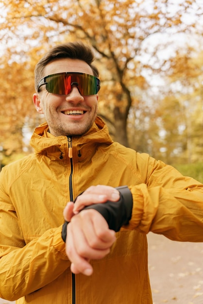 Um homem treina usando um relógio inteligente para esportes e óculos esportivos para correr Um atleta fazendo um aquecimento