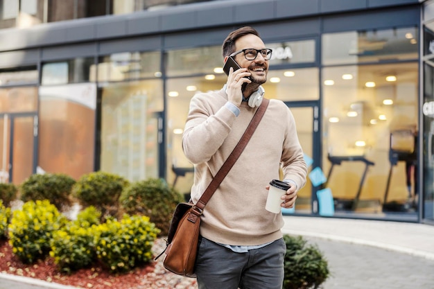 Um homem urbano sorridente falando ao telefone em uma rua