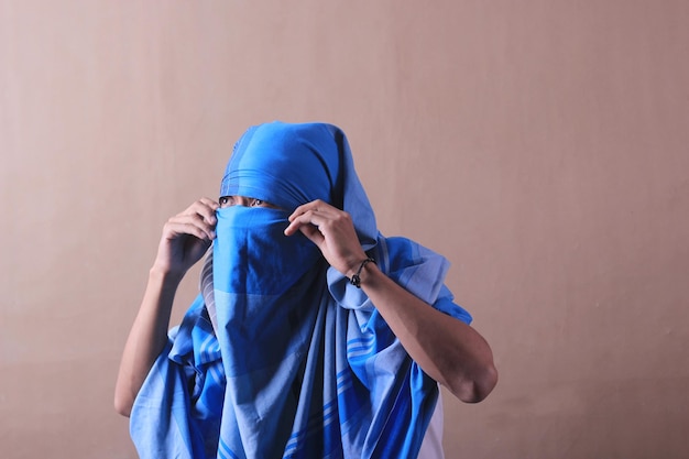 Um homem usando um lenço azul cobrindo o rosto.