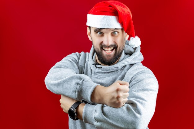 Um homem vestido com roupas de Natal está segurando um bastão de selfie com um telefone ligado a ele; ele está tirando uma selfie