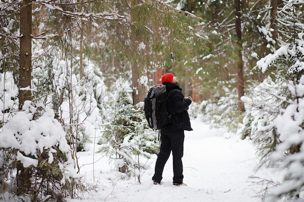 Um homem viaja com uma mochila. Caminhada de inverno na floresta. Turista em uma caminhada no inverno no parque.