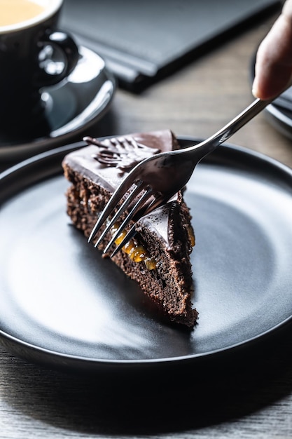 Foto um hóspede em um café corta um bolo sacher com um garfo