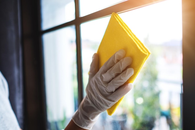 Um housekepper usando uma luva de proteção limpando a janela para o conceito de trabalho doméstico