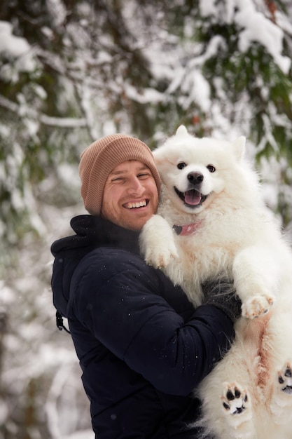 Um humano e um cachorro são melhores amigos Homem e cachorro andam na floresta nevada no inverno na neve profunda em um dia ensolarado