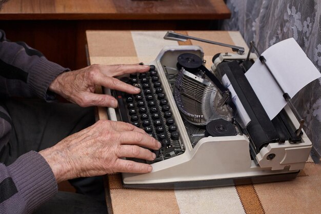 Um idoso escreve em uma máquina de escrever A máquina de escrever é velha