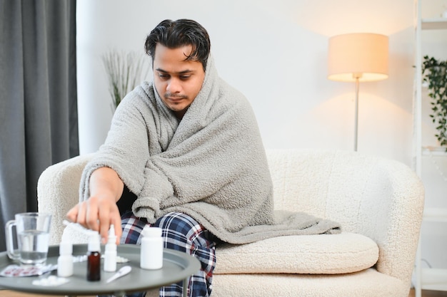 Um indiano doente de casaco senta-se sozinho a tremer de frio um árabe doente senta- se numa cadeira a sentir desconforto a tentar aquecer- se