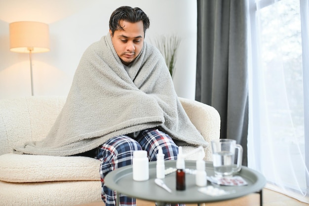 Um indiano doente de placas senta-se sozinho a tremer do frio um árabe doente senta-se numa cadeira a sentir-se desconfortável a tentar aquecer-se