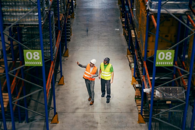 Um inspetor de armazenamento mostrando o local de trabalho para um novo trabalhador braçal