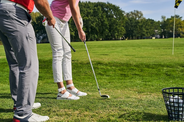 Um instrutor ensinando um jogador de golfe iniciante a assumir uma postura adequada de golfe