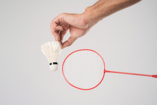 Um jogador de badminton em roupas esportivas fica segurando uma raquete e peteca