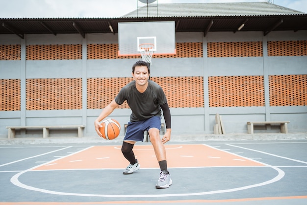 Um jogador de basquete executa um drible baixo entre as pernas, drible com a bola enquanto pratica b ...